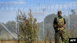 A guard stands at the border fence with barbed wire during a press tour to present military reinforcement measures at the border of Latvia with Russia, on August 16, 2024 near Karsava, Latvia.