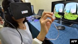 A journalist tries to use the new device using 3D-heptics technology which gives users tectale and kinethetic feeling virtually at a press preview in Tsukuba, suburban Tokyo on September 1, 2014. Japan's high-tech venture Miraisens unveiled a 3D technolog