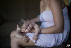 Gleyse Kelly da Silva holds her daughter Maria Giovanna as she sleeps in their house in Recife, Pernambuco state, Brazil, Jan. 27, 2016.