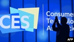 FILE - An attendee photographs a sign next to the CES logo at the 2020 Consumer Electronics Show in Las Vegas, Nevada, Jan. 6, 2020.