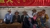 FILE - People rest in the shade under a government propaganda banner in Chinese and Tibetan in Lhasa, in China's Tibet Autonomous Region, on June 3, 2021. In a report released on May 22, 2024, Human Rights Watch says China is increasingly forcing rural Tibetans to move to cities.