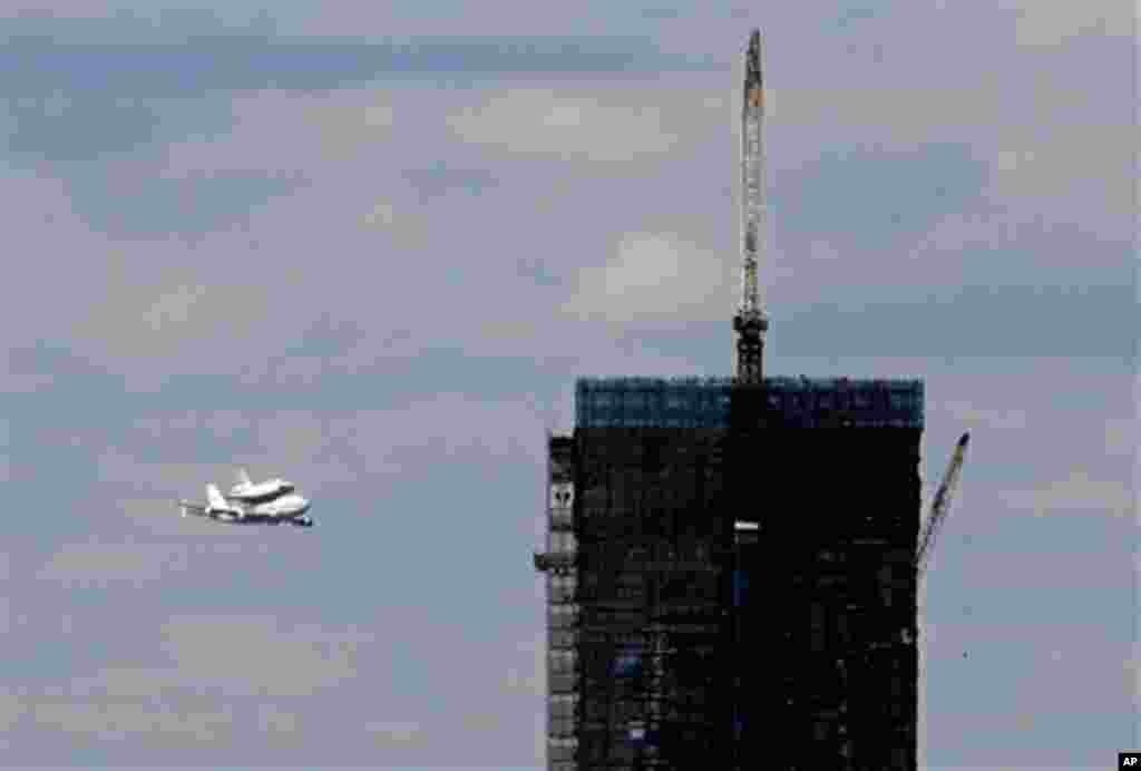 Space shuttle Enterprise, riding on the back of the NASA 747 Shuttle Carrier Aircraft, approaches the One World Trade Center building under construction, as it arrives in New York, Friday, April 27, 2012. Enterprise is eventually going to make its new ho