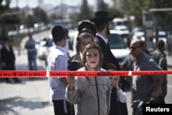 An Israeli boy stands behind the police line at the scene where a Palestinian youth stabbed and wounded a Jewish seminary student in Jerusalem, Oct. 8, 2015. The assailant was arrested at the scene, police said.