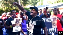 In this May 5, 2020, photo, Keith Smith speaks to a crowd as they march through a neighborhood in Brunswick, Ga. 