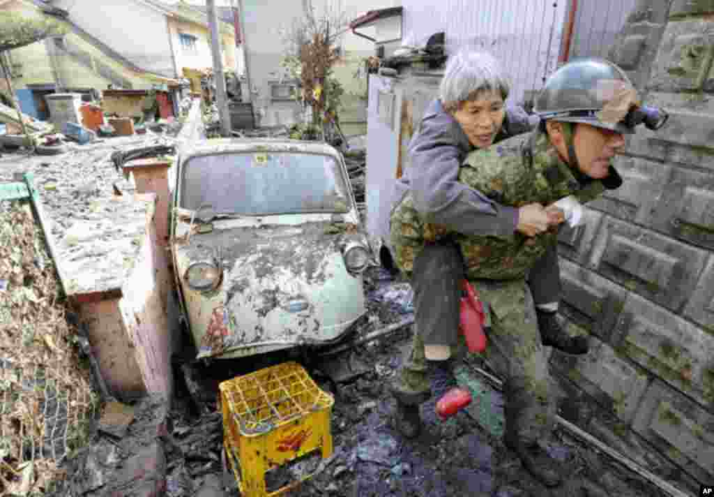 A woman who was trapped in her home is carried by a Japan Self Defense Force soldier in Kesennuma City in Miyagi Prefecture in northeastern Japan March 12, 2011. Japan confronted devastation along its northeastern coast on Saturday, with fires raging and 