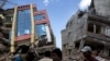 FILE - People walk past a collapsed building after a 7.3 earthquake struck, in Kathmandu, Nepal, May 12, 2015.