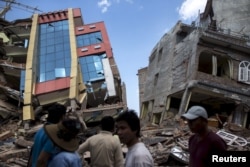 People walk past a collapsed building after a fresh 7.3 earthquake struck, in Kathmandu, Nepal, May 12, 2015.