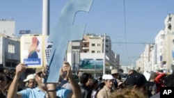 A protester holds up a cut-out of the letter "F" in an apparent recognition of the social network site Facebook's role in the recent revolts in Arab countries, Rabat, Morocco, March 20, 2011