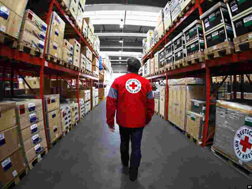 A German Red Cross member walks between medicine boxes and humanitarian aid at the Red Cross Logistic Center in Berlin, Germany, Friday, Jan 15, 2010 prior to an aid flight to Haiti. The German Red Cross chartered a plane to send a mobile Basic Help Care 