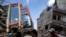 FILE - People walk past a collapsed building after a 7.3 earthquake struck, in Kathmandu, Nepal, May 12, 2015.