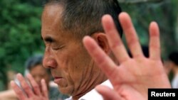 An elderly Chinese man practices early morning meditation in a Beijing park July 30.