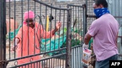 A volunteer from the Rays of Light NGO delivers food and cleaning products to an elderly woman living alone in Alexandra, Johannesburg, on April 16, 2020. 