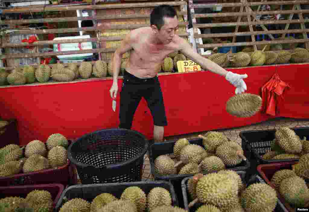 A durian seller throws a durian back into a basket at his stall in Geylang, Singapore. A group of National University of Singapore researchers have successfully produced wine from the tropical fruit that has a pungent aroma that is mouth-watering to some, revolting to others, using a fermentation process adapted from traditional wine making.