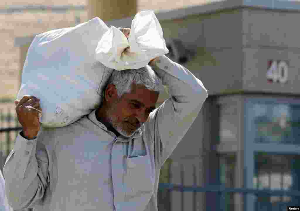 A Syrian man carries his belongings as he enters Turkey from the Turkish Cilvegozu border gate, Sept. 9, 2013.