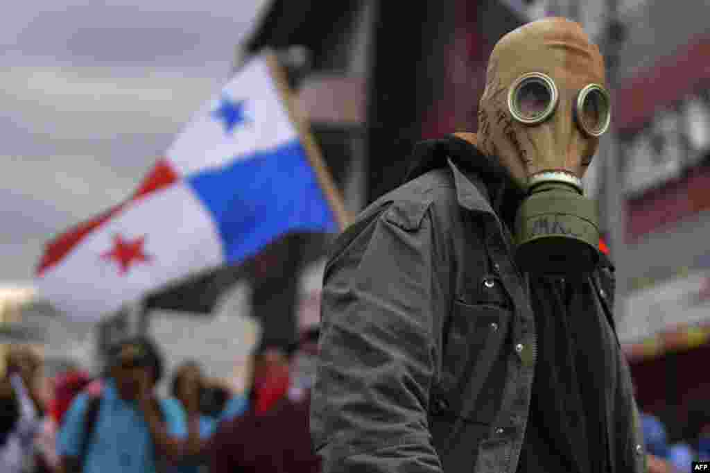 Un manifestante con una máscara de gas observa los enfrentamientos con la policía antidisturbios.