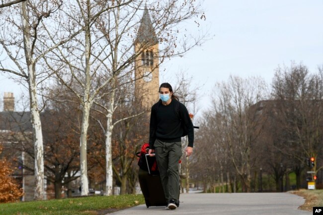 Cornell University sophomore, Kieran Adams, wheels his luggage through the university's campus in Ithaca, NY, Dec. 16, 2021, en route to go home after the university abruptly shut down all campus activities.