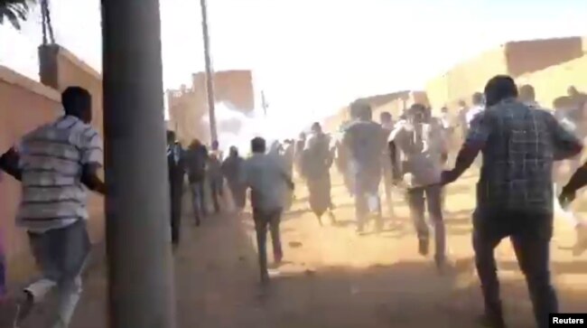 People run as tear gas canisters are thrown at them during an anti-government protest in Omdurman, Sudan, Jan. 9, 2019, in this still image taken from social media.
