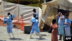 Health workers walk in an isolation center for people infected with Ebola at Donka Hospital in Conakry, April 14, 2014. 