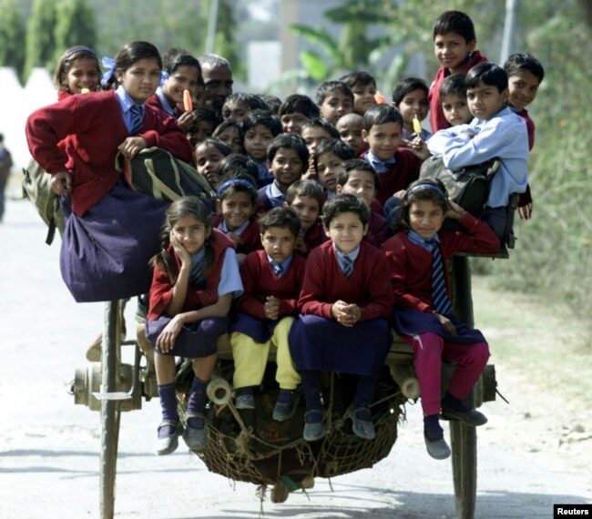 Anak-anak India naik kereta (semacam becak) dalam perjalanan pulang dari sekolah di pinggiran New Delhi, 26 Februari 2001. (REUTERS/Pawel Kopcznski/Files)