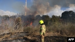 Petugas pertolongan pertama memadamkan kebakaran di tempat terbuka di Lod dekat Tel Aviv, yang dilaporkan disebabkan oleh rudal yang ditembakkan dari Yaman pada 15 September 2024. (Foto: AFP)