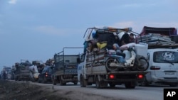 Truckloads of civilians flee a Syrian military offensive in Idlib province on the main road near Hazano, Syria, Dec. 24, 2019. 