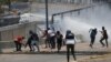 Anti-government protesters are sprayed with a water canon by security forces behind the perimeter wall of La Carlota airbase in Caracas, Venezuela, May 1, 2019.