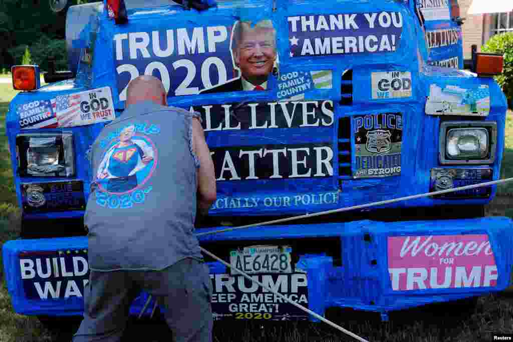 A supporter of U.S. President Donald Trump ties off a banner hanging from a boom during Super Happy Fun America&#39;s &quot;Back the Blue/President Trump Standout&quot; in Stoneham, Massachusetts, July 27, 2020.