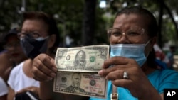 Una mujer muestra billetes de 50 dólares estadounidenses durante una protesta en Caracas, Venezuela. Foto de archivo. (AP/Adriana Cubillos)