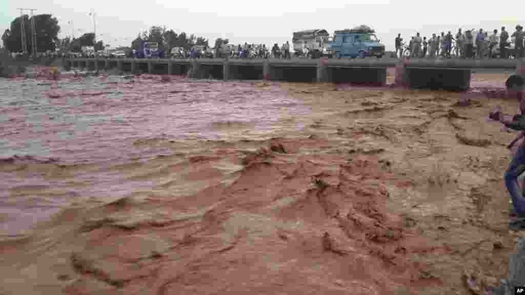 Cette image prise avec un téléphone portable montre résidents de Guelmim, au sud ouest du Maroc, en traversant un pont sur les eaux de crue, lundi 24 novembre 2014.