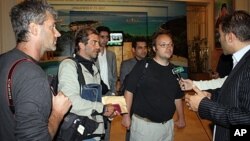 Freed journalists from Agence France Press (AFP) Roberto Schmidt (C) and Dave Clark (2nd-R) and Getty photographer Joe Raedle (L) speak to the press after their release in Tripoli, March 23, 2011