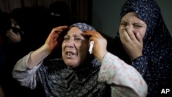 Palestinian mourners weep during the funeral of two-year-old, Rahaf Hassan, and her 30-year-old pregnant mother, Noor Hassan, who were killed in an Israeli air strike Sunday morning, during their funeral in the family house south of Gaza city, Oct. 11, 2015.