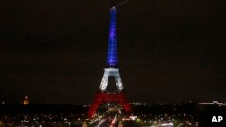 The Eiffel Tower is illuminated in the French national colors red, white and blue in honor of the victims of the terror attacks last Friday in Paris, Monday, Nov. 16, 2015. 