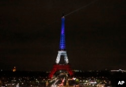 The Eiffel Tower is illuminated in the French national colors red, white and blue in honor of the victims of the terror attacks last Friday in Paris, Monday, Nov. 16, 2015.