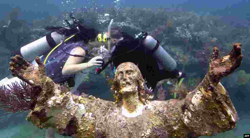 Kimberly Triolet (L) and Jorge Rodriguez kiss after being married next to the Christ of the Deep statue in the Florida Keys National Marine Sanctuary off Key Largo, Aug. 25, 2015.