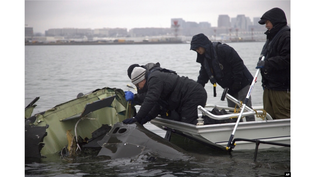 In this undated image provided by the National Transportation Safety Board, NTSB investigators and salvage crew members recover wreckage from the helicopter that collided with a jet on Jan. 29, 2025, near Ronald Reagan Washington National Airport.