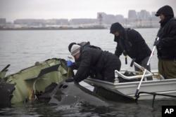 In this undated image provided by the National Transportation Safety Board, NTSB investigators and salvage crew members recover wreckage from the helicopter that collided with a jet on Jan. 29, 2025, near Ronald Reagan Washington National Airport.