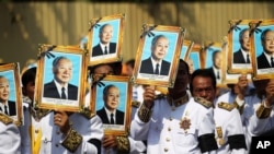 Procession participants shield themselves from the sun with portraits of the late former Cambodian King Norodom Sihanouk in a funeral procession in Phnom Penh, February 1, 2013.