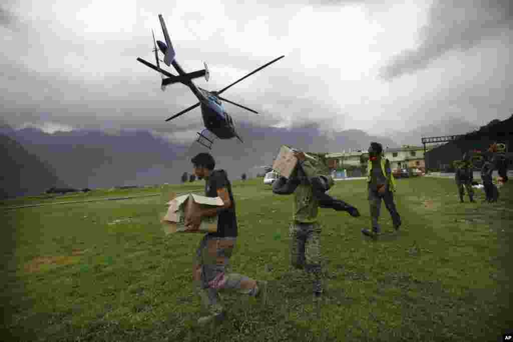 Civilians get ready to load relief material for flood affected victims on a helicopter in Joshimath, Uttarakhand, India, June 24, 2013.