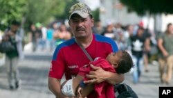 Seorang pria Honduras dengan menggendong putranya yang masih bayi berjalan ribuan kilometer menuju ke AS, Selasa (16/10).