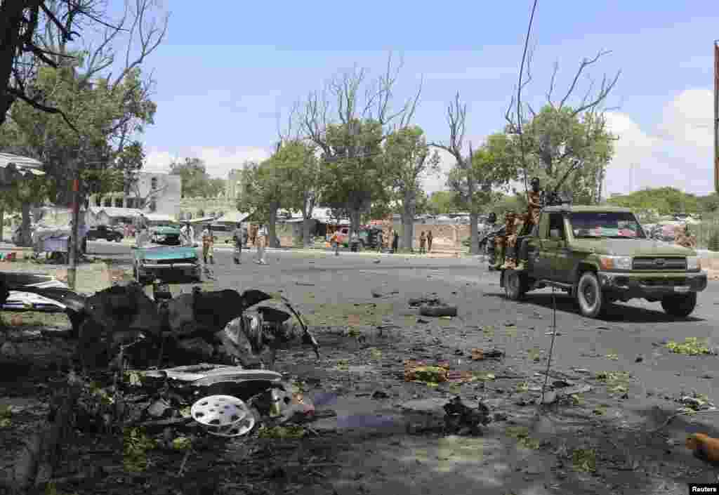 Somali government soldiers drive past the scene of a suicide car bomb attack next to a cafe in the suburbs of Mogadishu, Feb. 27, 2014. 