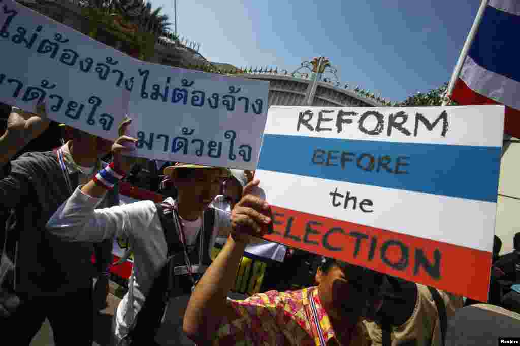 Anti-government protesters carry placards during a mass rally outside the house of Prime Minister Yingluck Shinawatra in Bangkok, Dec. 22, 2013.