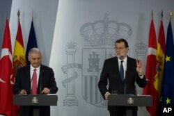 Turkey's Prime Minister Binali Yildirim, left, listens as Spain's Prime Minister Mariano Rajoy talks to journalists during a joint news conference with following a summit at the Moncloa palace in Madrid, April 24, 2018.