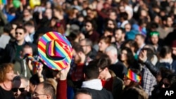 FILE - People are seen at a gay rights rally prior to a vote at the Italian parliament to change laws on recognition of rights for same-sex couples, in downtown Milan, Italy, Feb. 21, 2016.