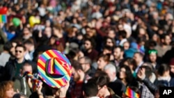 FILE - People are seen at a gay rights rally prior to a vote at the Italian parliament to change laws on recognition of rights for same-sex couples, in downtown Milan, Italy, Feb. 21, 2016.