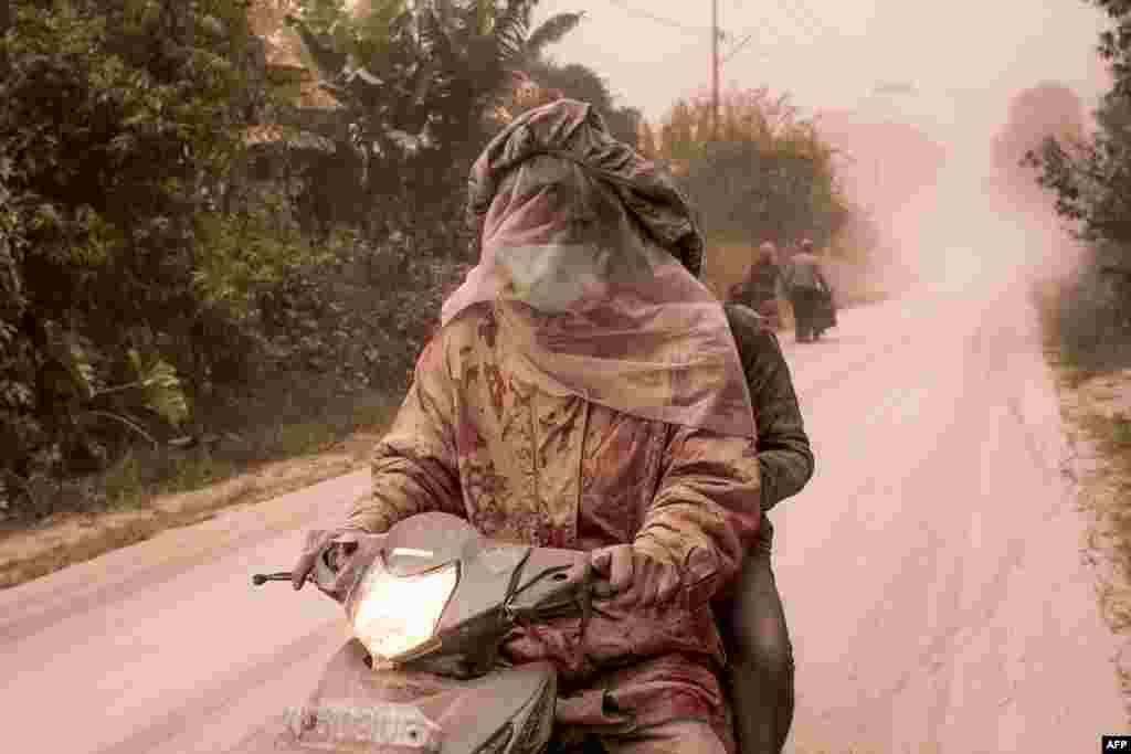 Pengendara sepeda motor menutup rapat wajah dan tubuhnya akibat hujan abu dari letusan Gunung Sinabung di Desa Tiga Pancur, Kabupaten Karo, Sumatra Utara.
