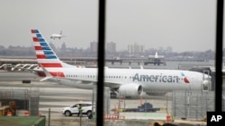FILE - An American Airlines Boeing 737 MAX 8 sits at a boarding gate at LaGuardia Airport in New York, March 13, 2019. American Airlines said on April 7, 2019 it is extending by over a month its cancellations of about 90 daily flights