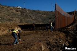 Workers on the U.S. side, paint a line on the ground as they work on the border wall between Mexico and the U.S., as seen from Tijuana, Mexico, Dec. 13, 2018.