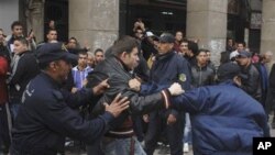 Riot police officers detain a protester during a demonstration in Algiers, February 19, 2011
