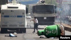 A protester throws stones at police vehicles in the Kurdish dominated southeastern city of Diyarbakir, Turkey, September 13, 2015. 