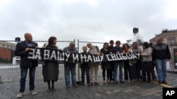 ARCHIVO - Activistas sostienen una pancarta que dice "Por vuestra libertad y la nuestra" durante un piquete en memoria de una manifestación de siete personas en 1968 en la Plaza Roja de Moscú, el domingo 25 de agosto de 2013.